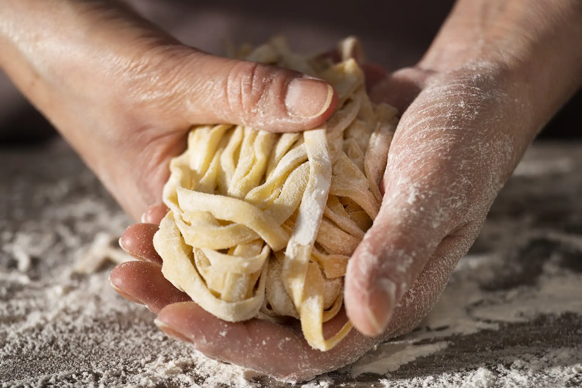 mani che tengono la pasta fresca fatta casa